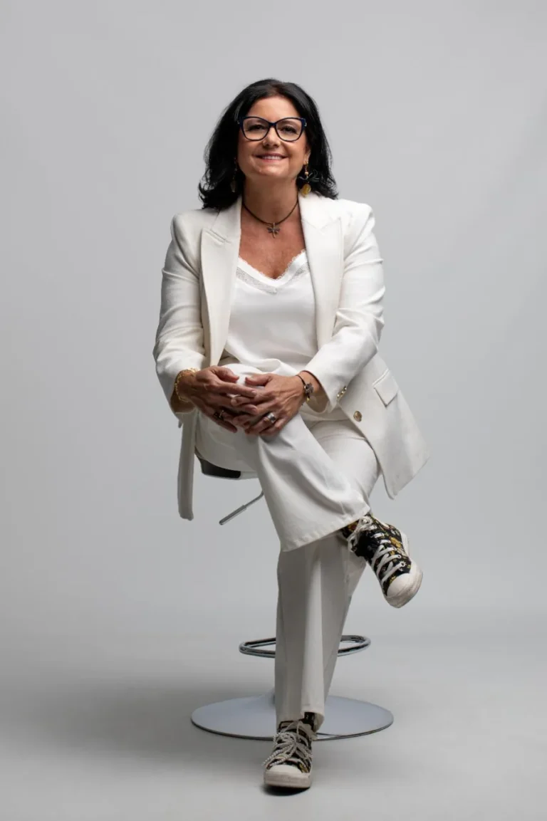 Azucena Meroño mirando a cámara, sentada con traje blanco